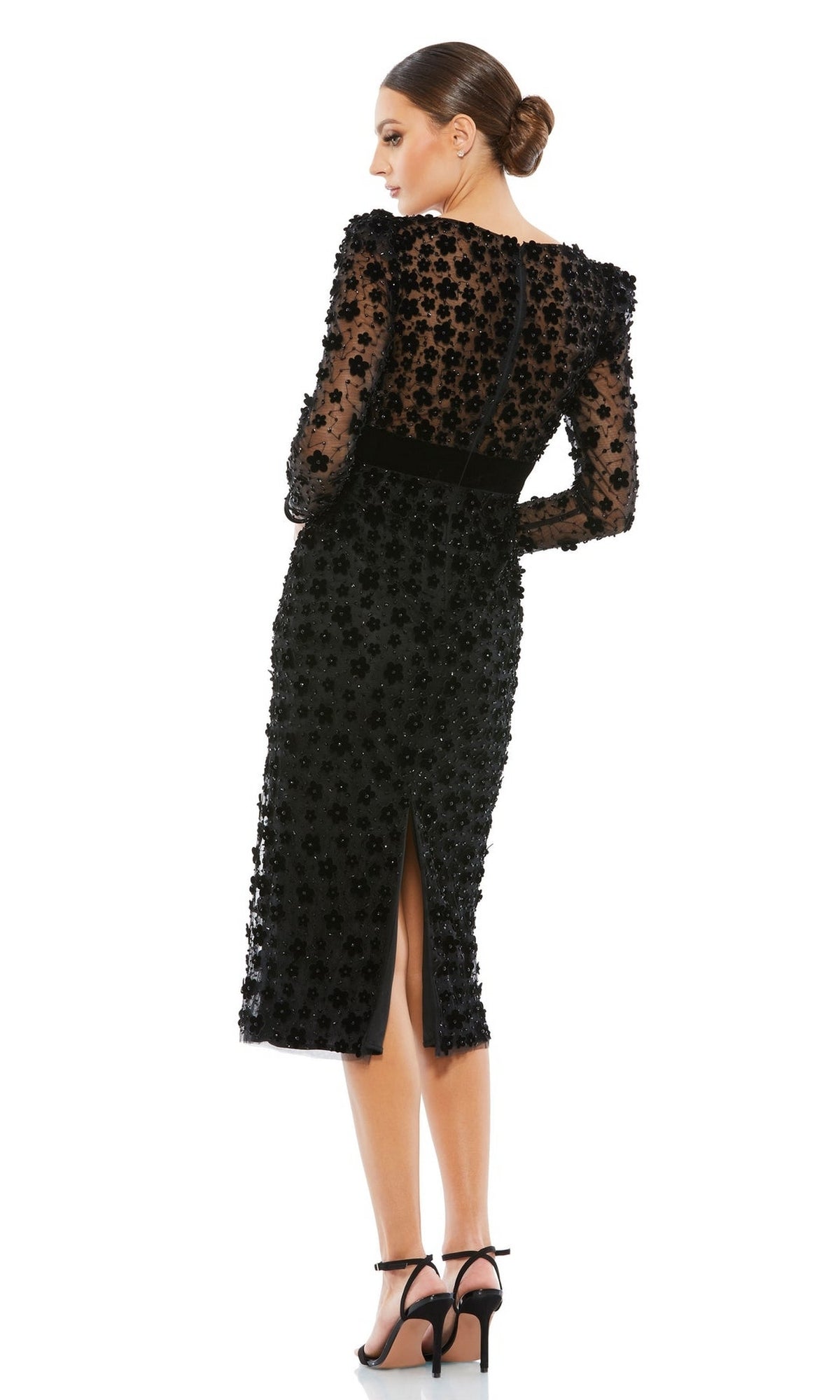 Woman in the Short Wedding Guest Dress 67856 by Mac Duggal—a black, semi-sheer, knee-length floral embellished dress with long sleeves, styled with a low bun—makes an elegant statement as a wedding guest.